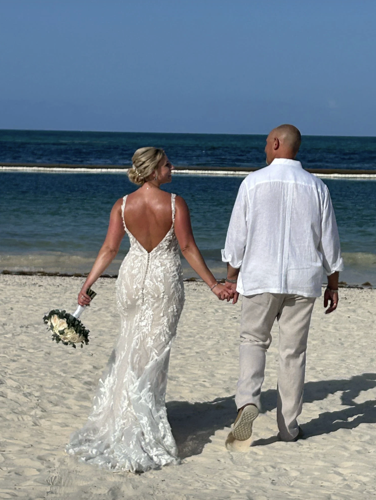 Bride and groom walking hand in hand on a Caribbean beach after their destination wedding ceremony.