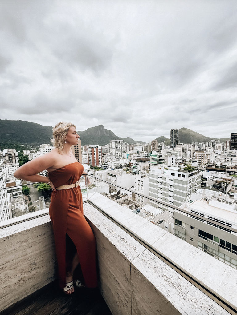 Amanda Dante overlooking Rio de Janeiro’s city skyline and surrounding mountains from a rooftop terrace.
