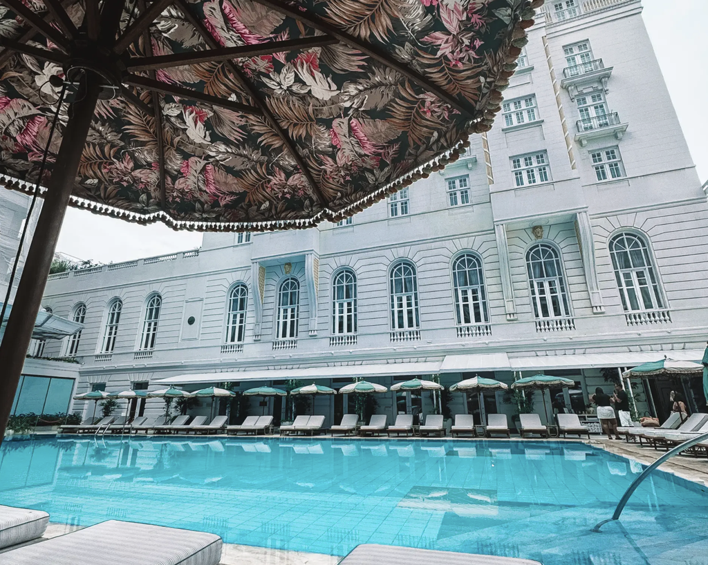 Swimming pool and loungers beneath patterned umbrellas at Copacabana Palace, A Belmond Hotel, in Rio de Janeiro.