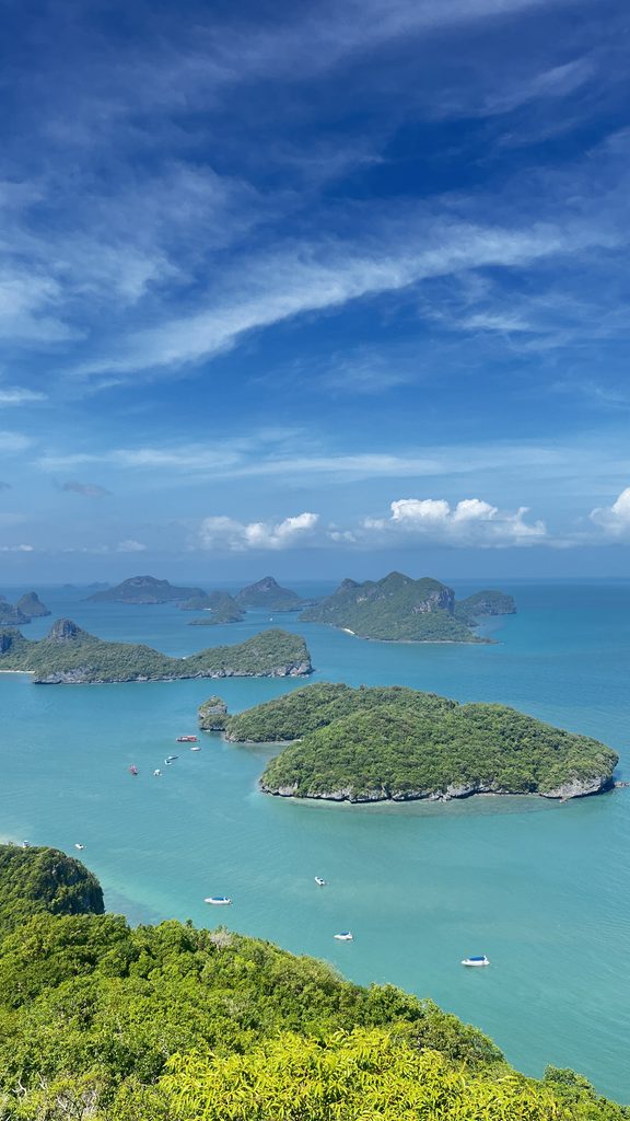 Panoramic view of lush islands surrounded by turquoise water beneath a blue sky in Thailand.