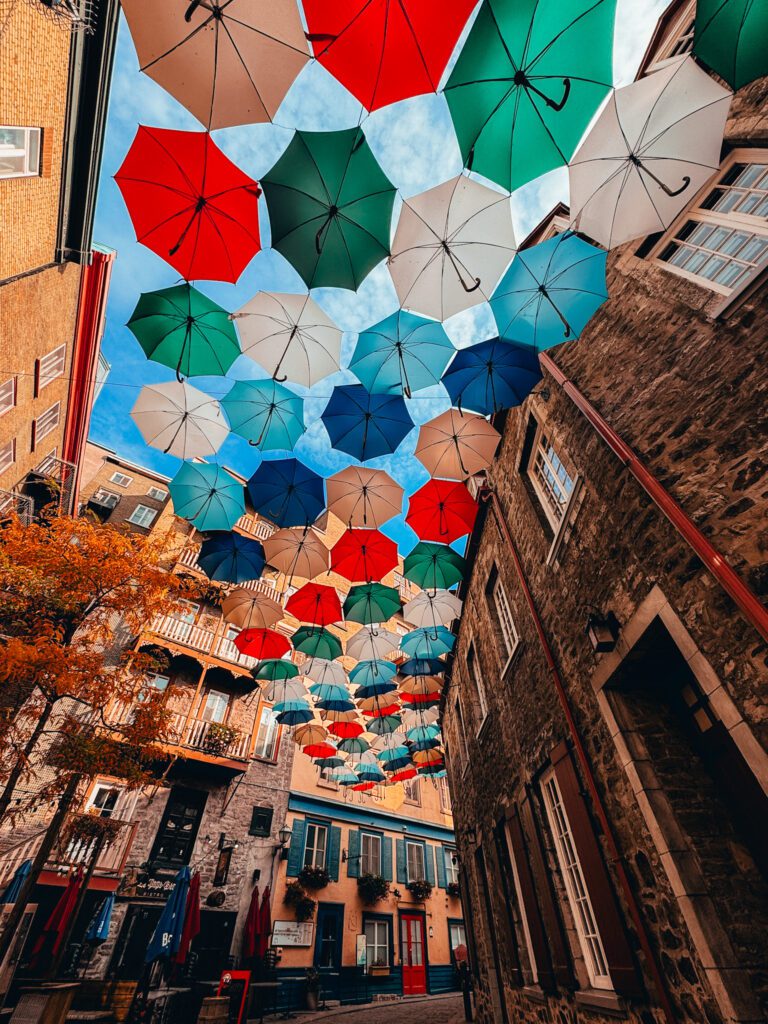 Colorful umbrellas hanging above a cobblestone street in Old Québec City